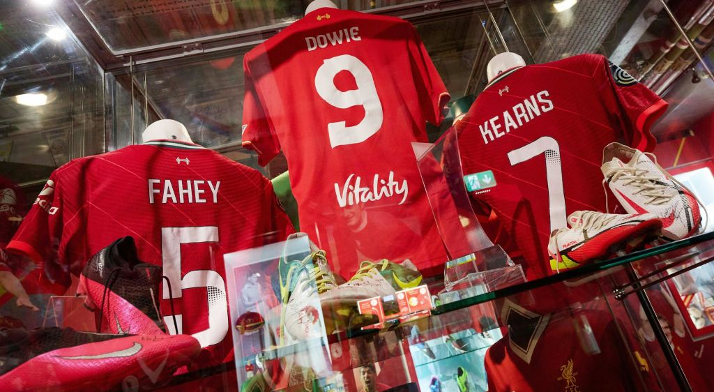 "Dowie", "Mahey", "Kearns" 라는 이름을 가진 세 개의 빨간색 스포츠 유니폼이 신발 및 기타 스포츠 기념품과 함께 유리 뒤에 전시되어 있습니다.