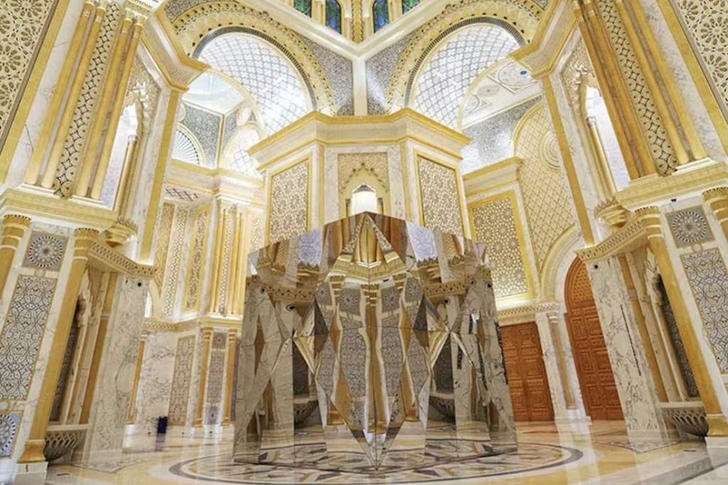 아치형 천장과 정교한 디테일이 돋보이는 웅장하고 도금 처리된 인테리어의 화려하고 반사적인 기하학적 조형물입니다.