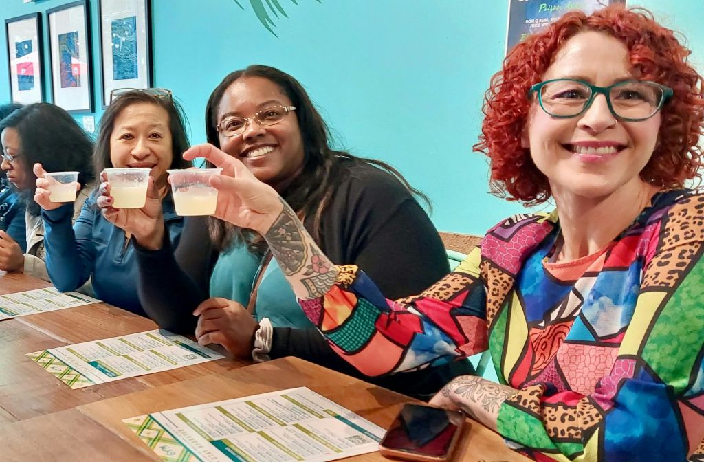 청록색 벽을 배경으로 메뉴가 있는 테이블에서 미소를 짓고 작은 컵에 음료를 들고 있는 두 사람.