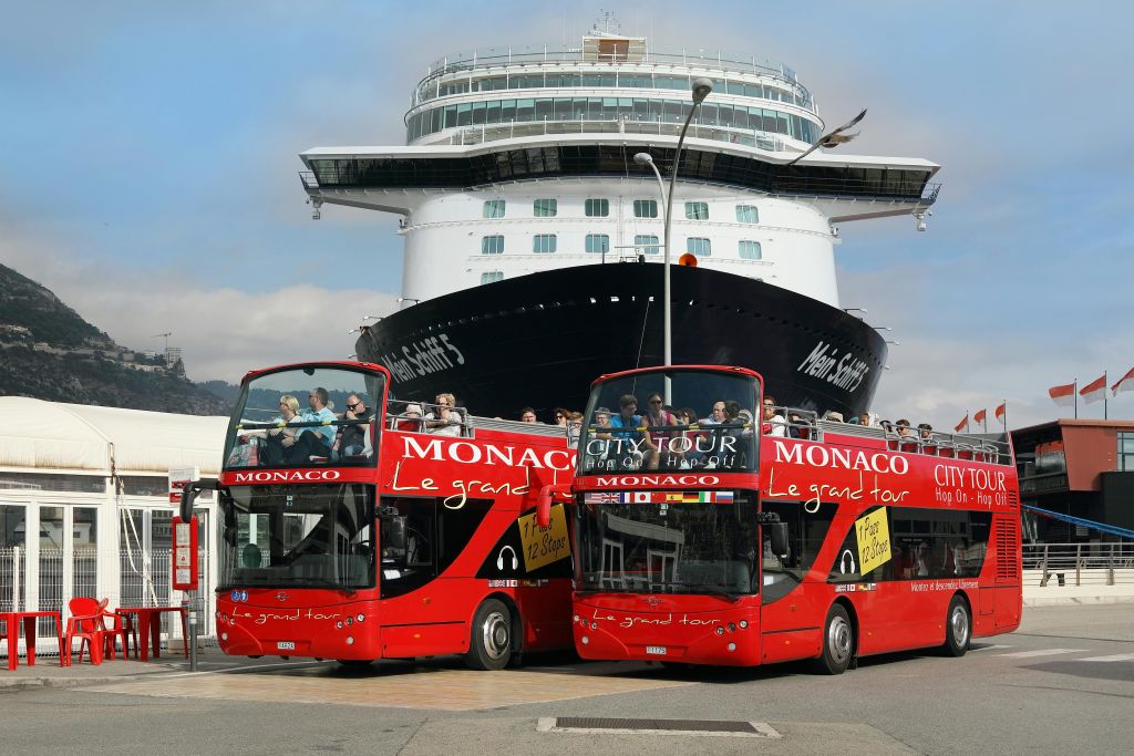 선착장에 있는 대형 유람선 앞에서 "모나코 르 그랜드 투어" 라고 표시된 빨간색 2층 투어 버스 두 대.