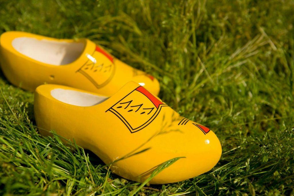 빨간색과 검은색 디자인의 밝은 노란색 나무 막힘이 녹색 잔디 위에 놓여 있습니다.