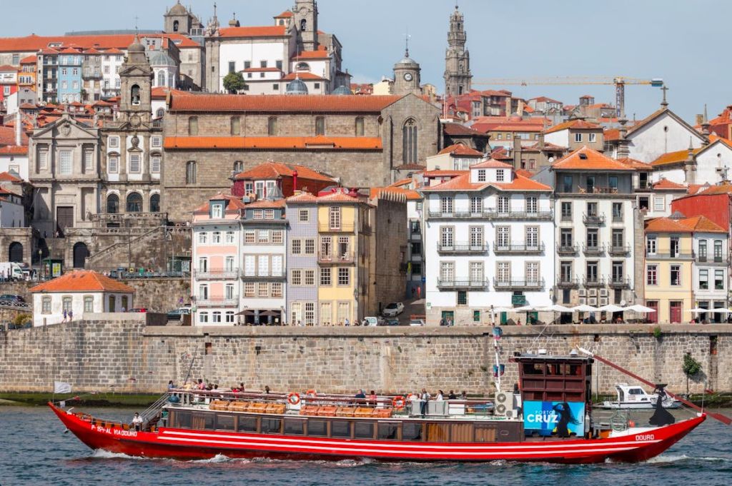 유럽 도시의 강을 따라 화려하고 유서 깊은 건물이 있는 투어 보트를 타고 지나갑니다. 우뚝 솟은 교회 건물이 배경으로 보입니다.