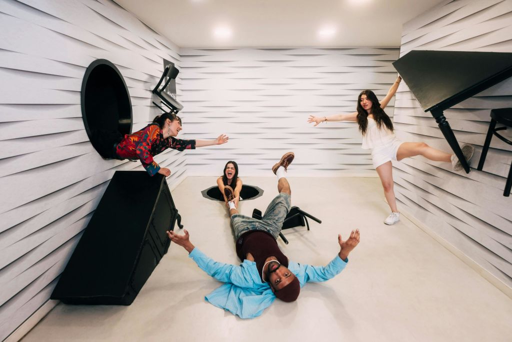 착시 현상이 있는 유쾌하고 기울어진 방에서 상호 작용하는 네 사람은 바닥을 닮은 벽을 특징으로 합니다.