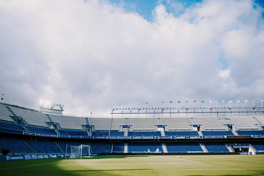 파란색 좌석이 있는 빈 축구 경기장, 녹색 필드의 골대, 흐린 하늘 아래 스탠드에 있는 배너.