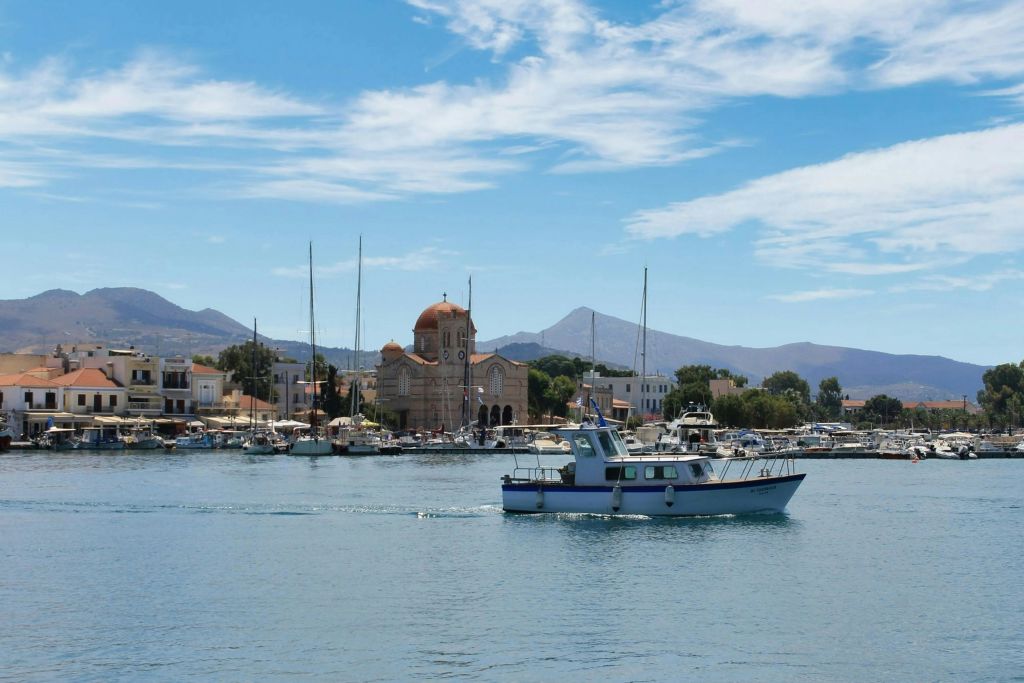 마을, 돔이 있는 교회, 산을 배경으로 고요한 바닷가를 항해하는 작은 어선입니다.
