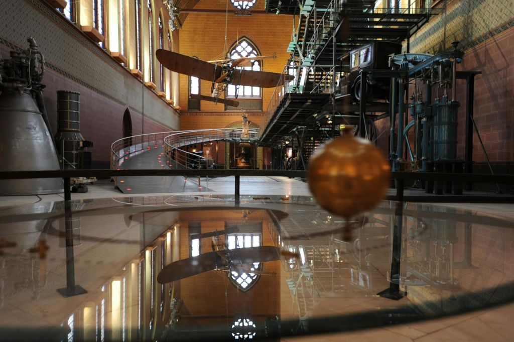 벽돌 벽, 아치형 창문, 철제 계단이 있는 인더스트리얼 스타일의 건물 내부에 진자가 보입니다.