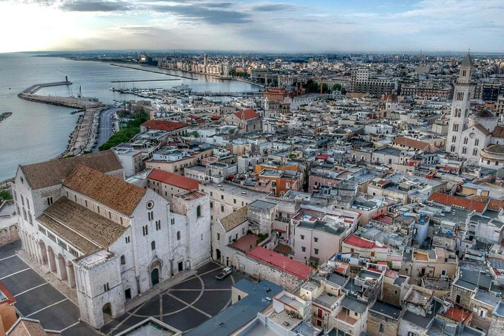 빽빽한 건물, 유명한 교회, 바닷가, 흐린 하늘이 있는 해안 도시의 공중 전망.