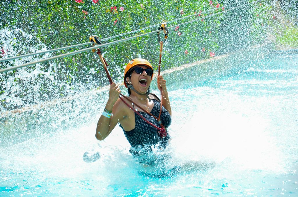 검은색 수영복과 주황색 헬멧을 착용하고 팔을 들어 올린 사람이 지퍼 안감을 대고 물에 튀고 있습니다.