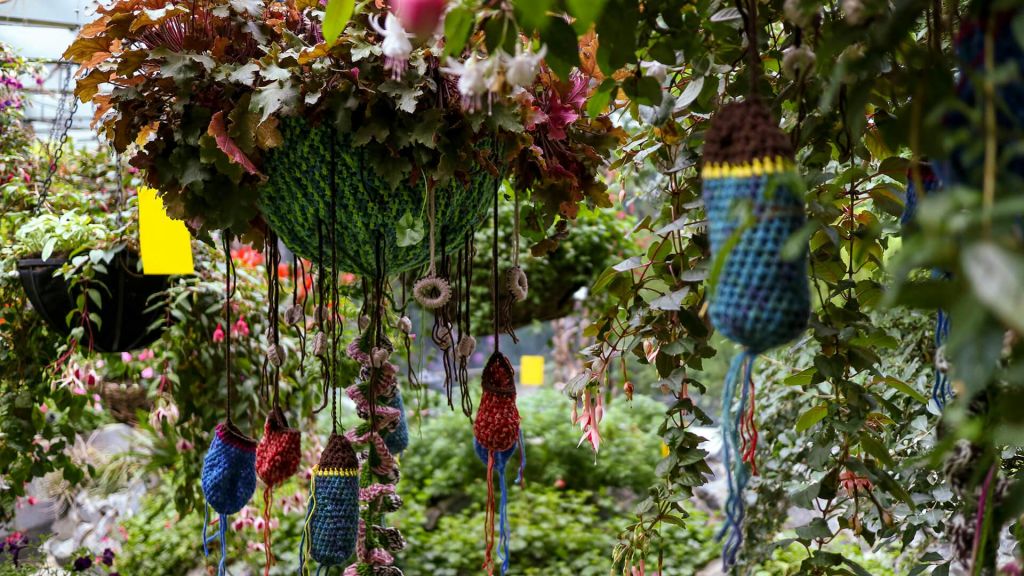 활기찬 녹지와 꽃을 배경으로 꾸며진 정원에는 크로셰 장식과 울창한 식물이 걸려 있습니다.