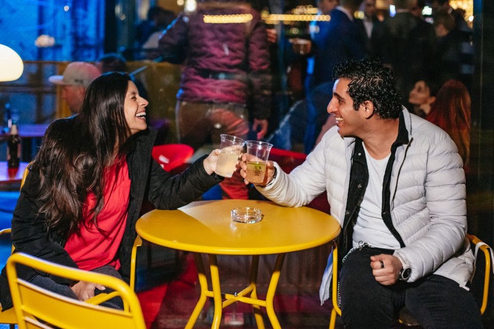 웃는 여자와 웃는 남자가 클럽에서 컵을 쥐고 있다.