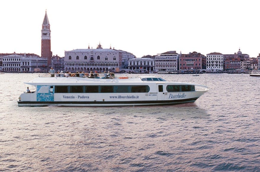 '베네치아 - 파도바' 라는 이름의 보트가 유서 깊은 베네치아 건물을 배경으로 물줄기를 가로지르고 있습니다.