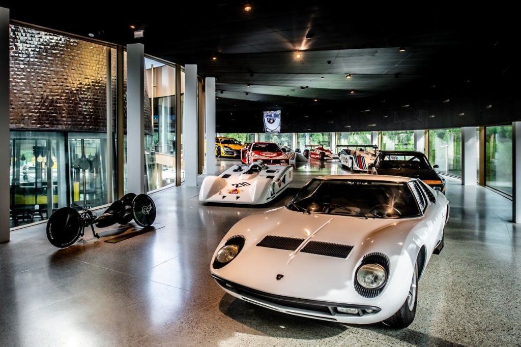 전경에 흰색 람보르기니를 비롯하여 다양한 빈티지 및 레이싱 카가 전시된 자동차 전시실.