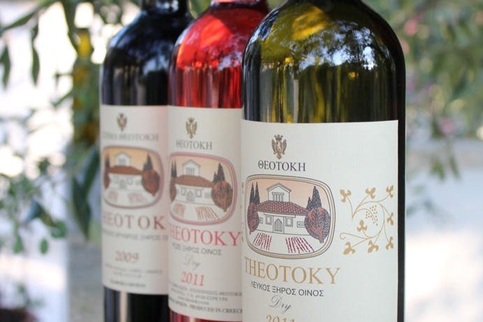 하우스와 포도원 디자인이 특징인 라벨이 부착된 와인 3병. 레이블은 그리스어 텍스트로 2009 년과 2011 년을 나타냅니다.