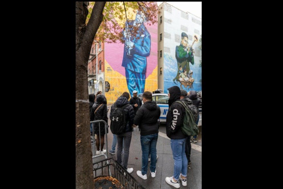 할렘의 상징적인 그림 앞에 서 있는 투어 게스트의 매혹적인 사진.