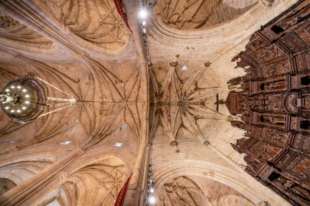 정교한 석조 늑골이 있는 금고와 오른쪽에 목조 구조물이 있는 고딕 양식의 성당 천장의 내부 전망.