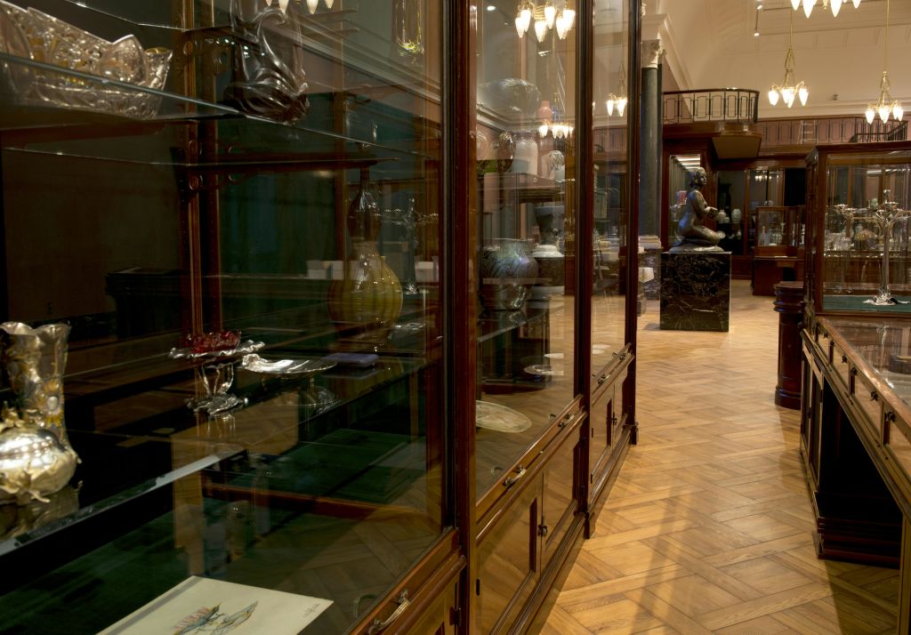 각종 유물과 화병을 수록한 나무 진열 케이스와 동상이 배경으로 보이는 박물관 홀.