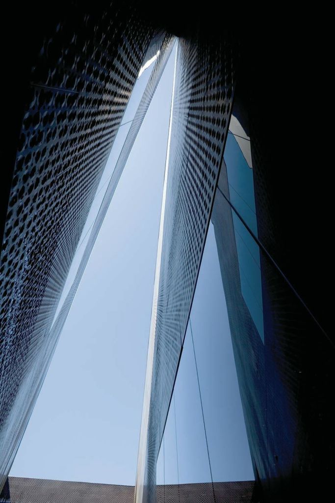 높고 현대적인 반사 건물로 사이 간격이 좁아 위쪽의 하늘을 보여줍니다.