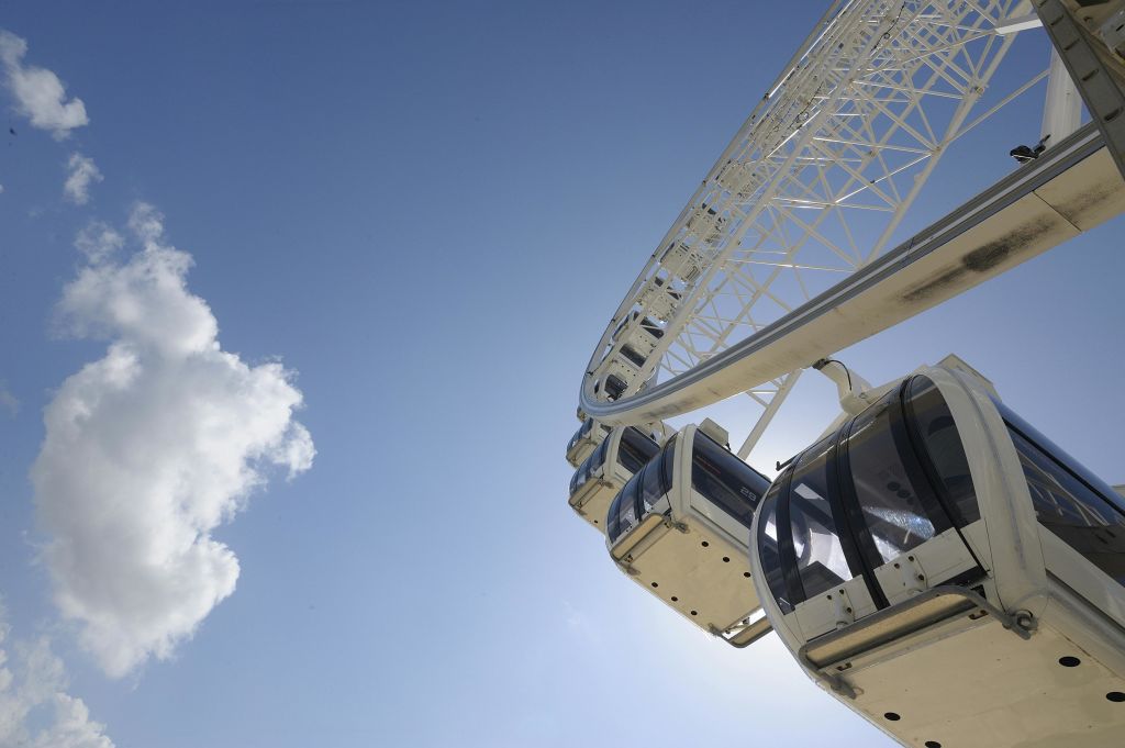 구름이 흩날리는 푸른 하늘을 배경으로 대관람차 선실이 클로즈업됩니다.