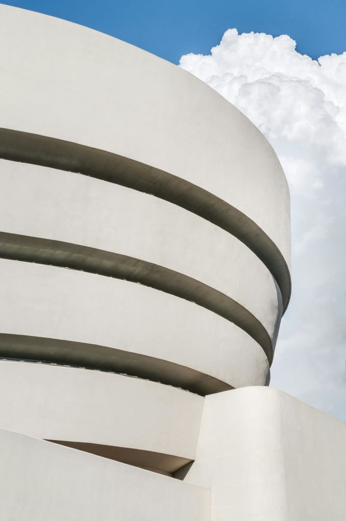 흐린 하늘을 배경으로 수평선을 이루는 현대적인 복층 건물의 곡선형 흰색 외관.