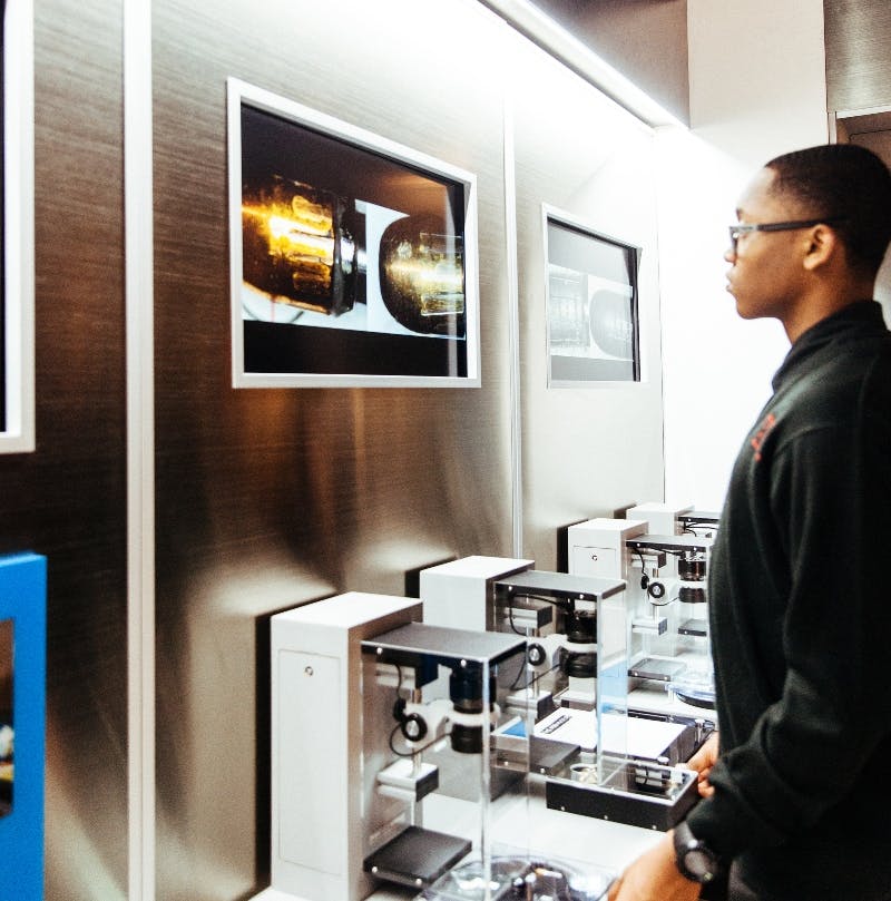 한 사람이 세련되고 현대적인 전시실에서 첨단 장비 디스플레이와 스크린을 살펴보고 있습니다.