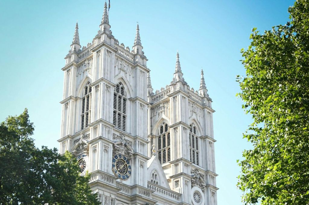화창한 날 커다란 아치형 창문과 정교한 디테일이 돋보이는 화려하고 하얀 고딕 양식의 타워 2개, 전면에 나무가 있습니다.