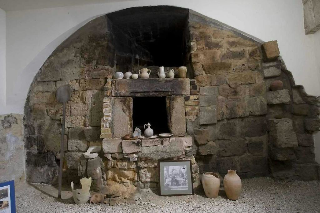 저그, 그릇, 액자 사진 등 다양한 도자기가 전시된 고대 석조 오븐.