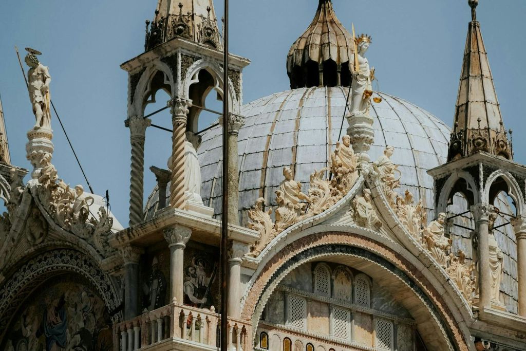 돔형 지붕, 아치, 동상, 청명한 하늘을 배경으로 화려한 디테일이 돋보이는 정교한 건축물.