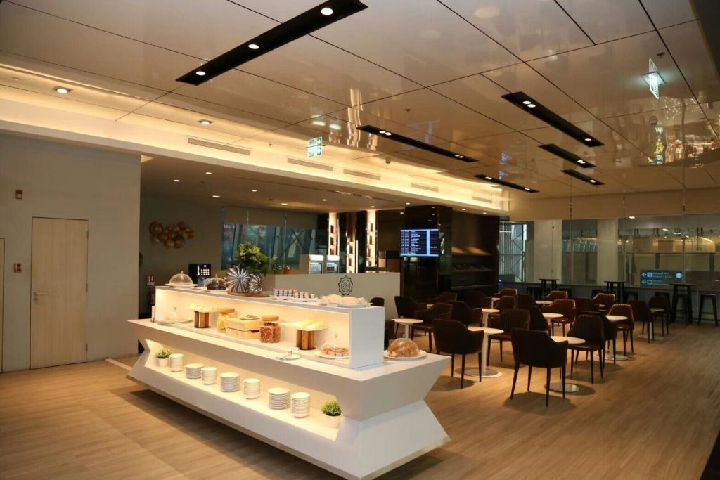 음식과 접시가 있는 뷔페 카운터가 있는 현대적인 라운지 인테리어는 좌석과 세련된 조명으로 둘러싸여 있습니다.