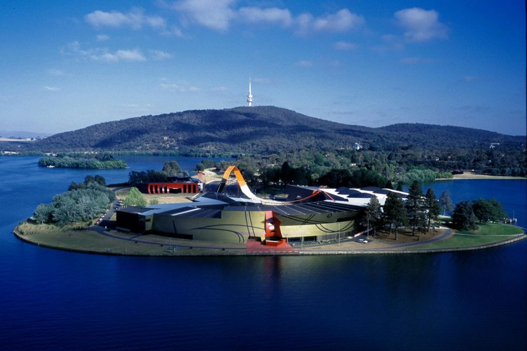 저 멀리 언덕과 탑이 있고 녹지로 둘러싸인 호수 근처의 예술적인 디자인이 돋보이는 현대적인 건물의 공중 전망.