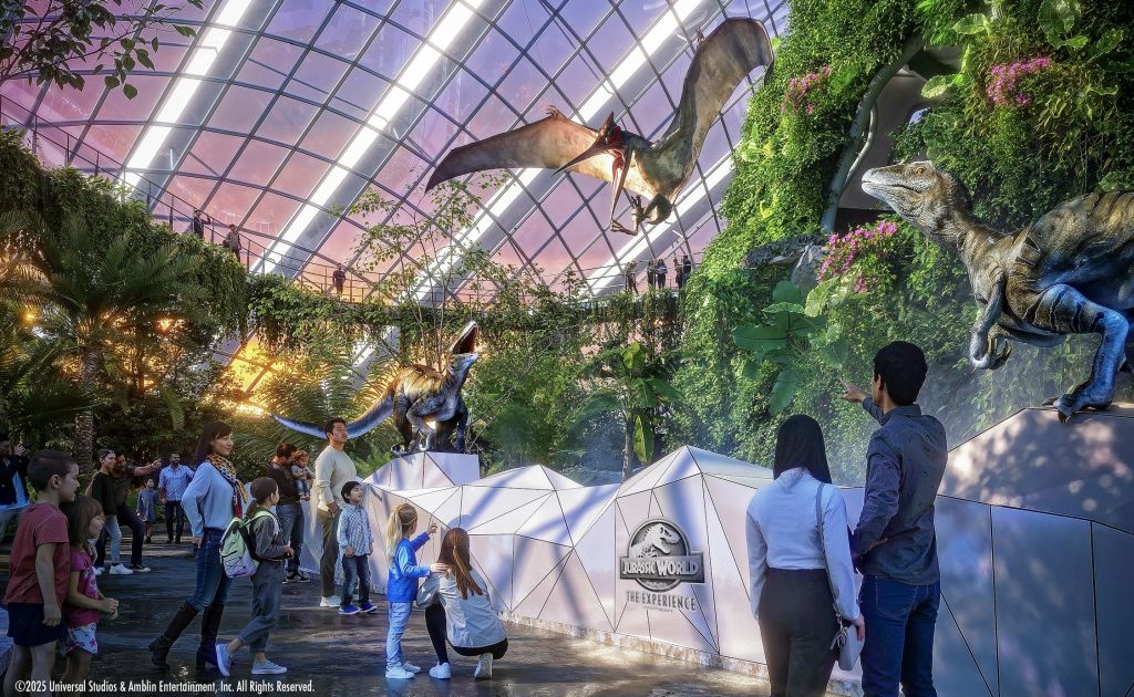 사람들은 울창한 식물과 "쥬라기 월드 (Jurassic World)" 로고가 있는 미래형 유리 천장 전시관에서 애니마트로닉스 공룡을 관찰합니다.