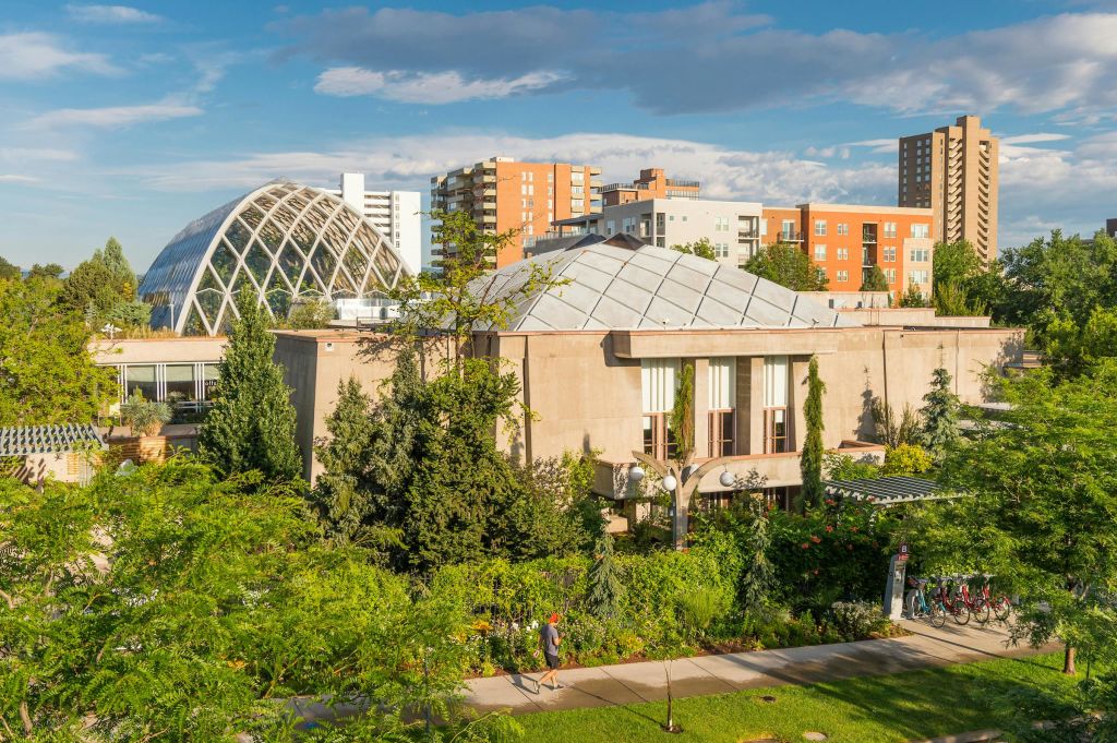기하학적인 돔 지붕과 전경의 울창한 녹지, 그리고 여러 개의 현대식 건물을 배경으로 한 건물입니다.
