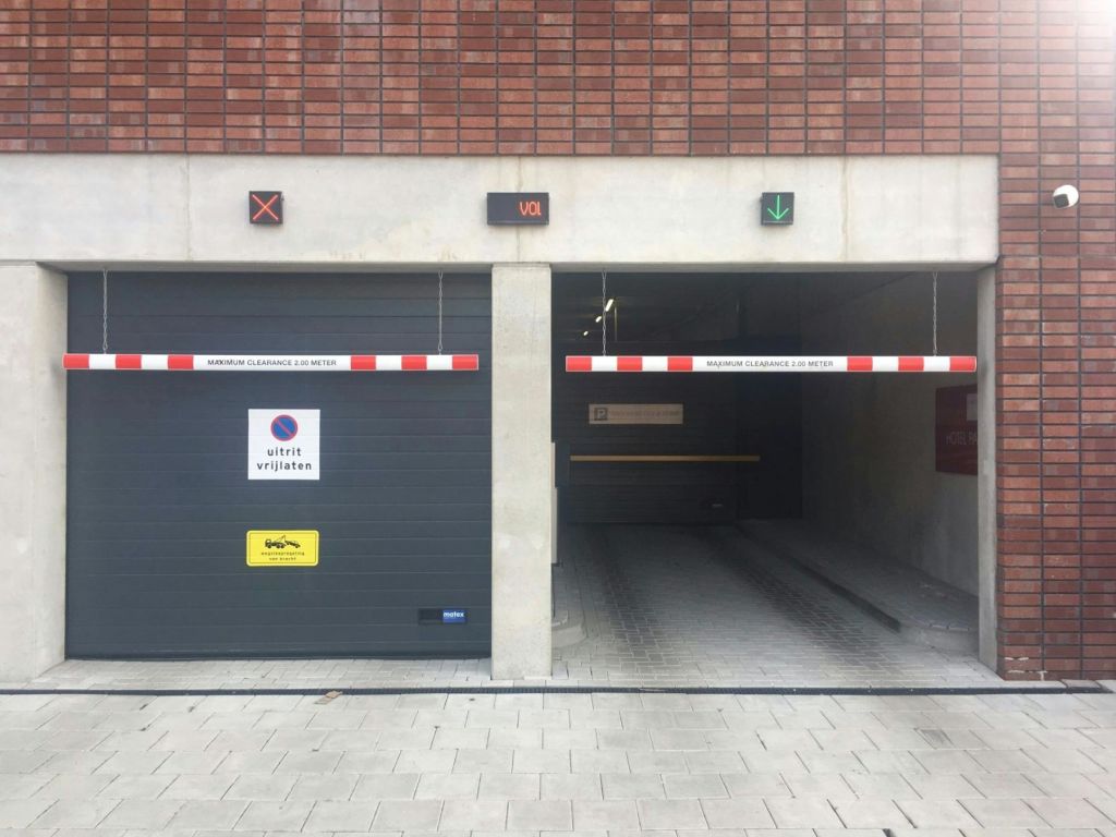 빨간색과 흰색 장벽이 있는 두 개의 차고 입구. 하나는 닫힌 문과 표지판이 있고 다른 하나는 위의 녹색 화살표로 열려 있습니다.