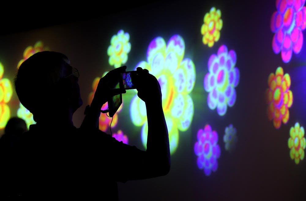 벽에 화려하고 빛나는 꽃 모양의 무늬를 촬영하는 사람의 실루엣.