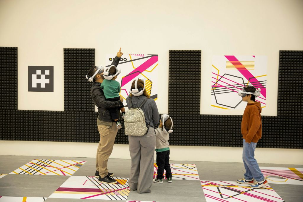 벽과 바닥에 화려한 기하학적 예술품이 있는 아트 갤러리에서 VR 헤드셋을 착용한 한 무리의 사람들.