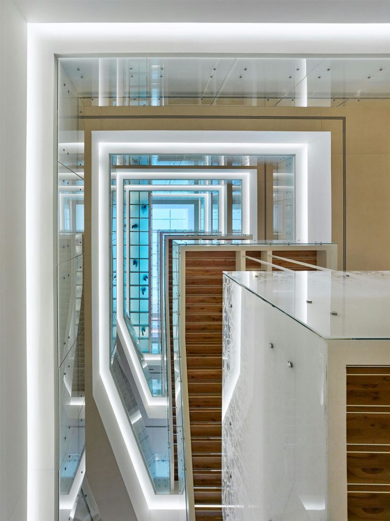 기하학적 디자인, 유리 난간, 자연광을 반사하는 가장자리 주변의 조명 흰색 프레임이 있는 현대적인 다층 인테리어.