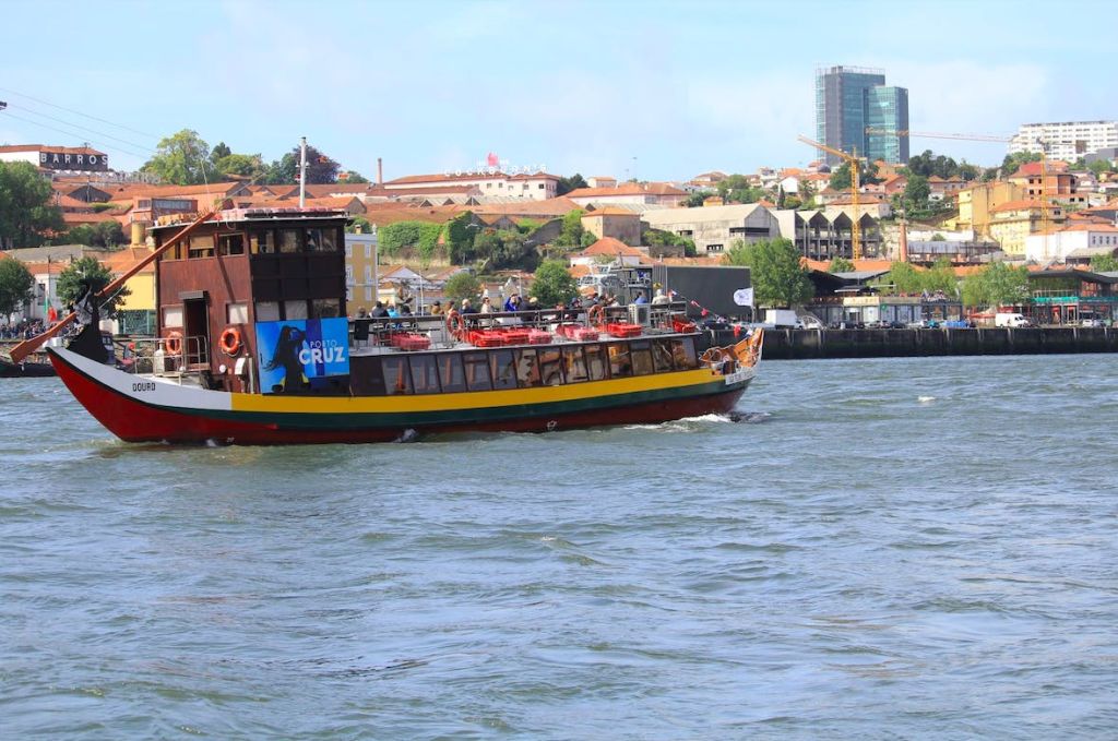 도시 풍경을 배경으로 건물과 녹음이 우거진 강에서 크루즈를 즐기는 투어 보트.