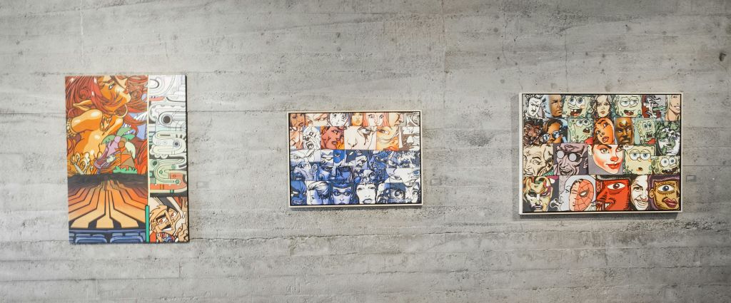 콘크리트 벽에 놓인 액자에 담긴 작품으로, 파란색과 주황색으로 된 컬러 섹션과 함께 다양한 표정으로 그려진 얼굴의 격자가 특징입니다.