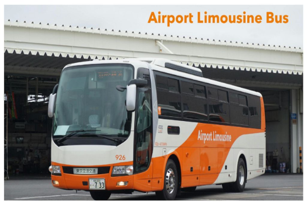 '공항 리무진' 이라고 표시된 주황색과 흰색 버스가 주름진 지붕이 있는 건물 근처에 주차되어 있습니다.