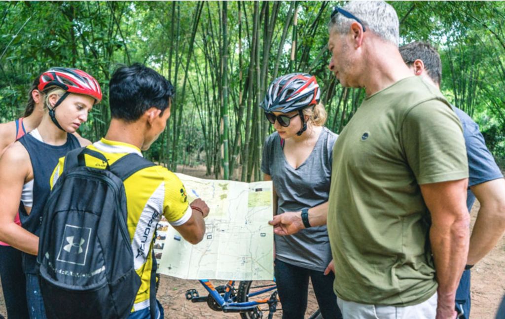 자전거를 배경으로 대나무 숲의 지도를 살펴보는 4인조 사이클링 장비.