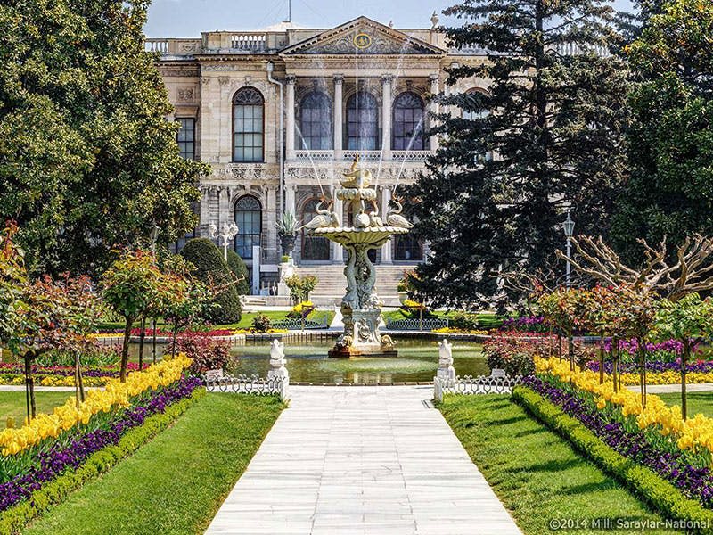 아치형 창문, 조경된 정원, 중앙 통로, 조각품이 있는 화려한 분수가 있는 유서 깊은 건물입니다.