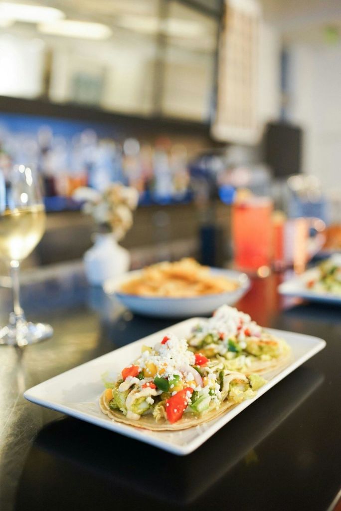 음료와 음식을 배경으로 바 카운터에 놓인 접시에 타코를 곁들여보세요.