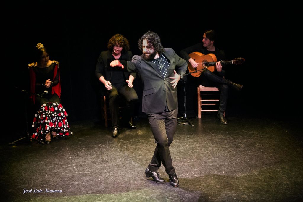 무용수가 무대에서 기타리스트를 포함한 3명의 뮤지션과 함께 플라멩코를 연주합니다.