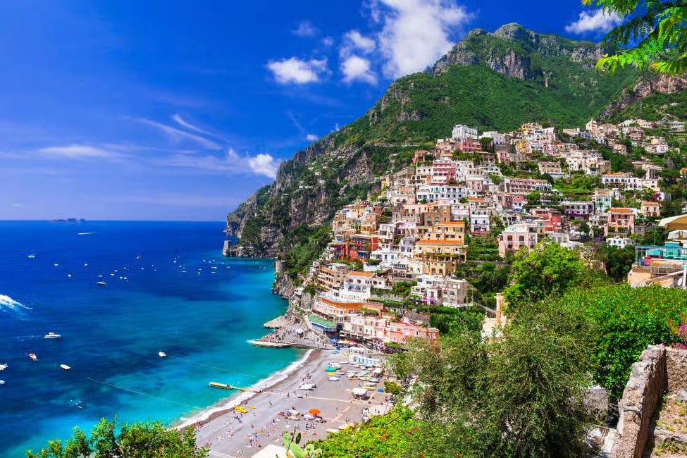 청명한 하늘 아래 활기찬 푸른 바다에 인접한 가파른 언덕에 빽빽한 건물이 있는 다채로운 해안 마을.