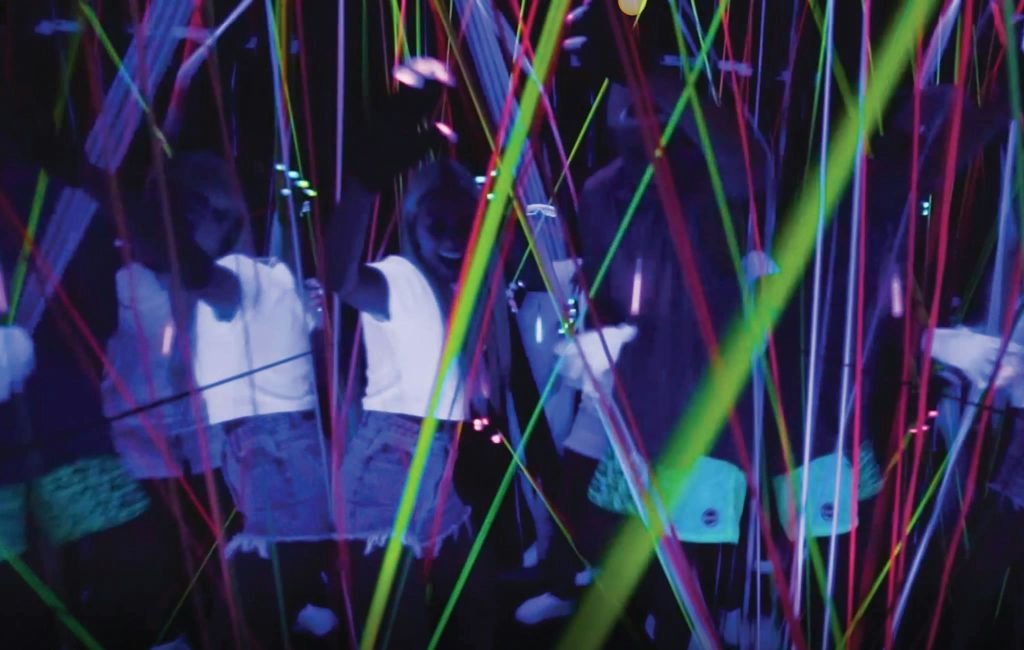 다채로운 레이저 빔과 반사로 활기차고 활기찬 분위기를 연출하는 네온 조명 방을 즐기는 사람들.