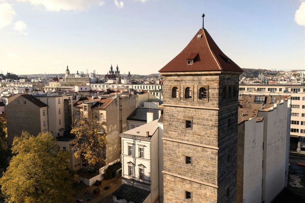 전경에는 맑은 하늘 아래 도시 건물로 둘러싸인 붉은 지붕의 석탑이 있습니다.