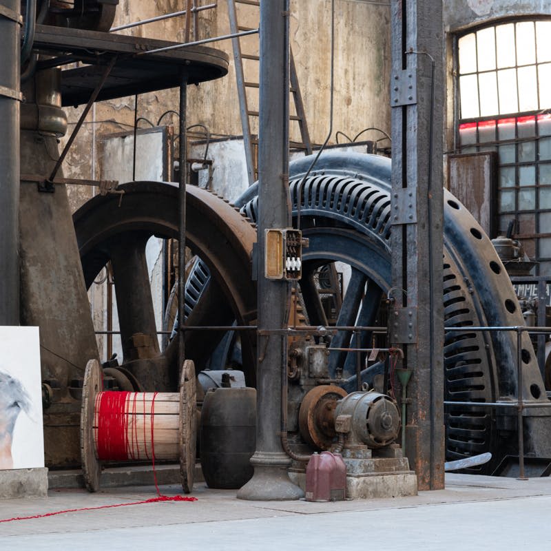 대형 기계, 빨간색 와이어 스풀, 창문을 배경으로 한 오래된 산업 작업장.
