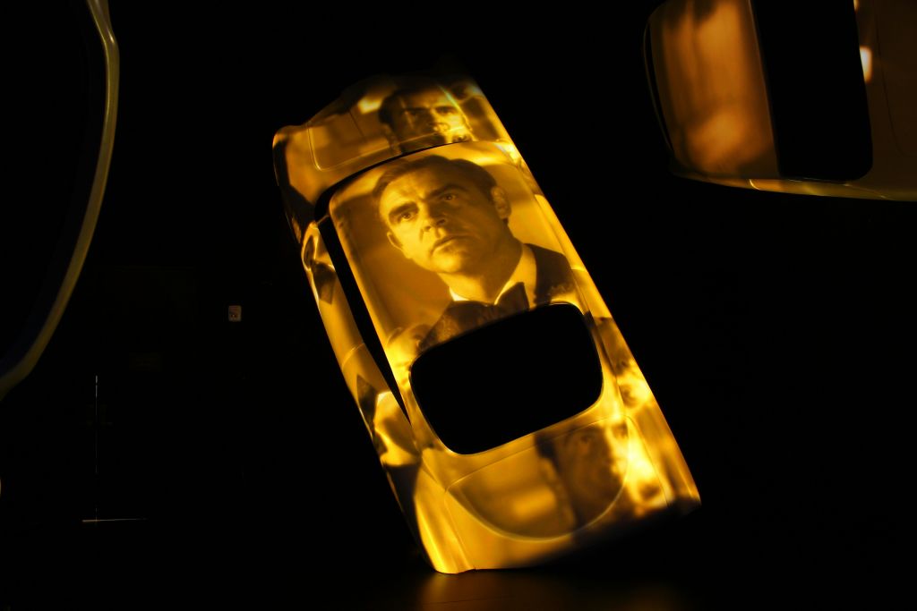 노란색 빛과 어두운 배경에 정장을 입은 남자의 이미지를 투영한 기울어진 자동차.