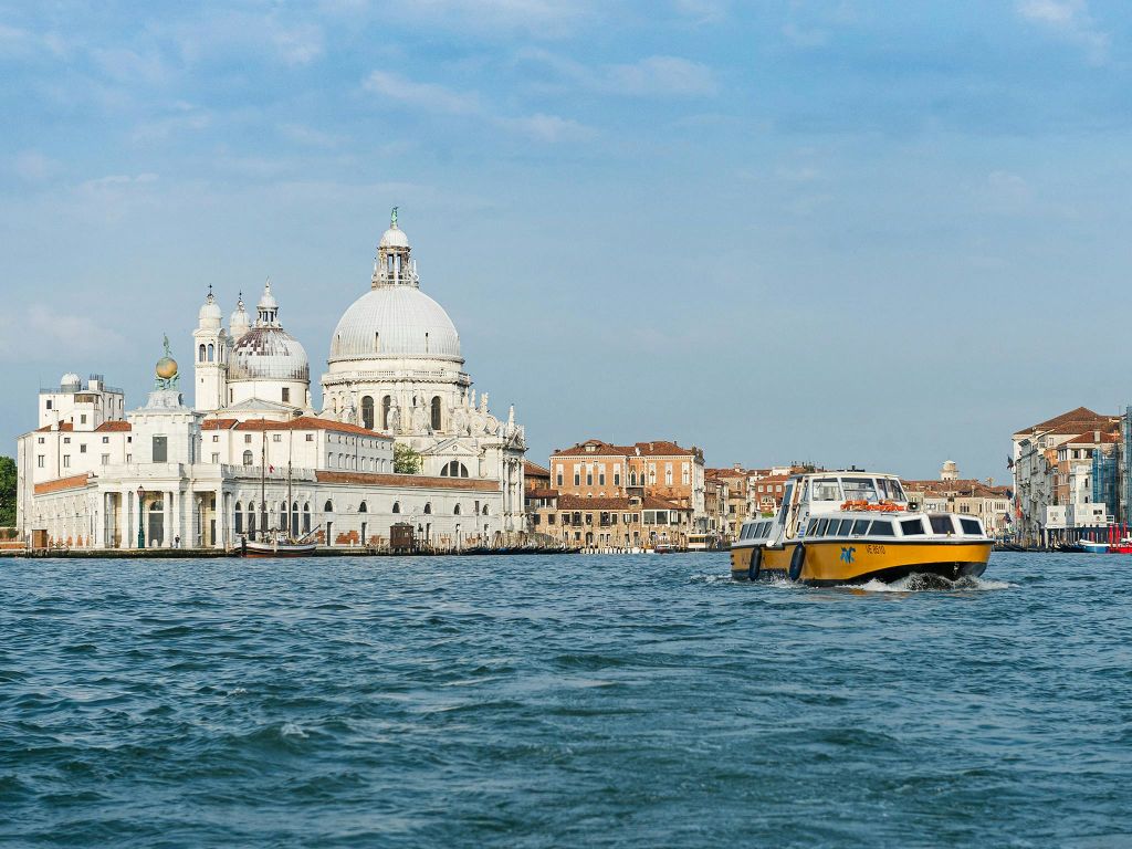 옐로우 워터 택시는 넓은 운하를 따라 큰 돔형 건물과 유서 깊은 건축물을 배경으로 운행됩니다.