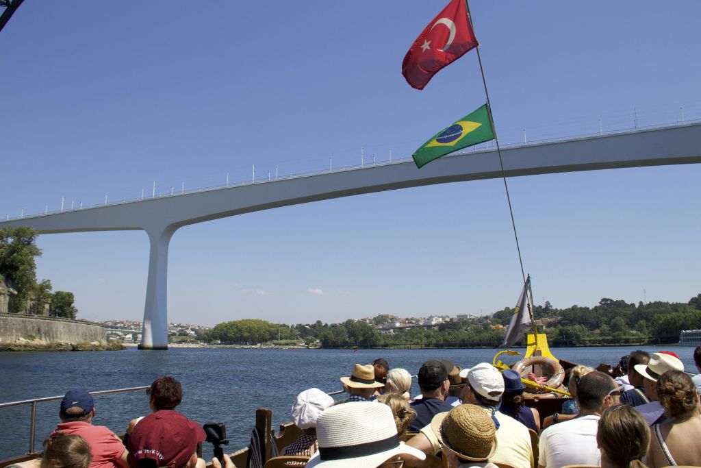 터키와 브라질 국기가 달린 현대적인 아치형 다리 아래에서 보트를 타고 맑고 푸른 하늘을 배경으로 즐기는 투어입니다.