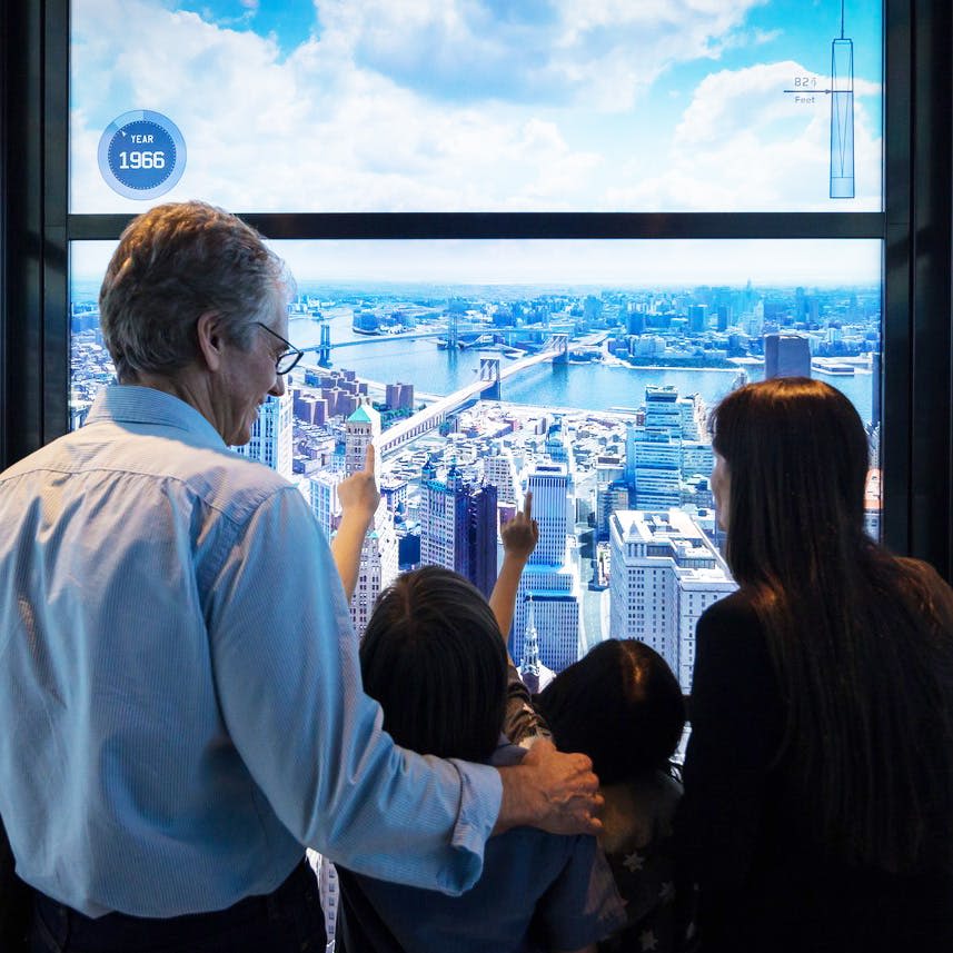 왼쪽 상단에 "1966" 이라는 연도가 표시된 높은 관점에서 도시 풍경의 디지털 디스플레이를 바라보는 한 남성과 세 명의 어린이.